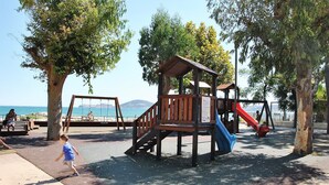 A playground with a wooden play structure, a red slide, and a blue slide. - Dinky Home Air-conditioned Penthouse With sea View Terrace (Formia)