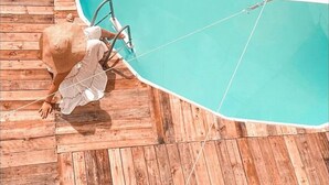 A person sitting by a pool with a wooden deck. - Family Suite - Apartment 1 in Villa Coconut (Samaná)