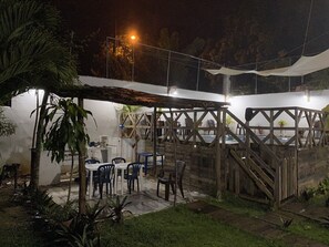 An outdoor patio area with tables and chairs, a pool, and a covered seating area. - Family Apartment - Apartment 5 in Villa Coconut (Samaná)