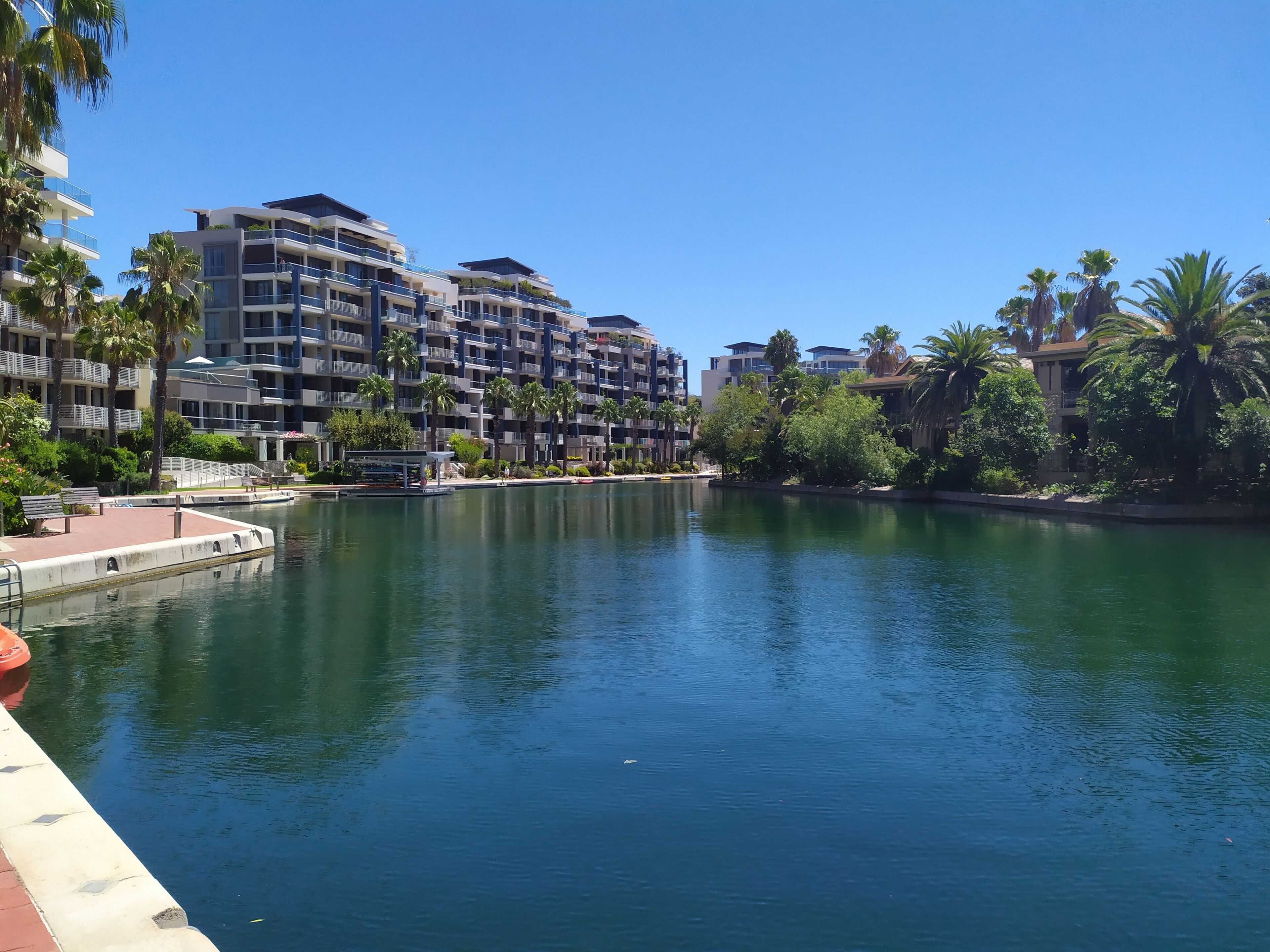 A waterfront hotel with multiple balconies, a dock, and lush greenery.