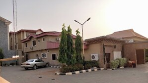 A parking lot with a car, a building with multiple floors, and a street lamp. - Room-choice Gate Hotel-guest Suite (Benin City)