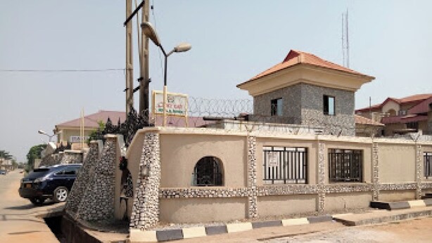 A residential building with a gated entrance, a small tower-like structure, and a paved driveway. - Room-choice Gate Hotel-guest Suite (Benin City)