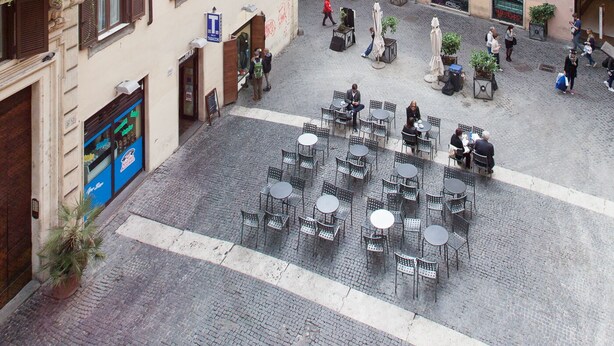 A courtyard with outdoor seating, surrounded by buildings with multiple windows and balconies. - Charming Apartment Campo De'fiori (Rome)