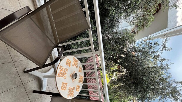 A patio area with a round table and chairs, surrounded by a white metal railing. - Room in Studio - Beautiful Room in Limenaria, Only Five Minutes Away From Center (Thasos)