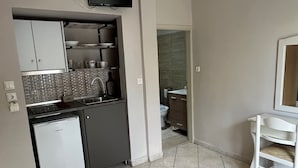 A compact kitchen with a refrigerator, sink, and a flat-screen TV mounted above the counter. - Room in Studio - Beautiful Room in Limenaria, Only Five Minutes Away From Center (Thasos)