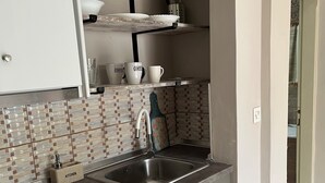 A compact kitchen with a built-in refrigerator, a sink, and a tiled backsplash. - Room in Studio - Beautiful Room in Limenaria, Only Five Minutes Away From Center (Thasos)