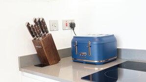 A kitchen with a blue toaster, a knife block, and a wall socket. - Alexandra Palace Luxury Serviced Apartments In St Albans (St Albans)