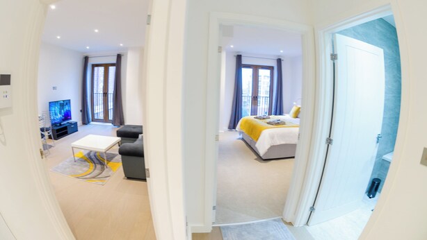 A modern hotel room with a television, sofa, and bed. - Alexandra Palace Luxury Serviced Apartments In St Albans (St Albans)