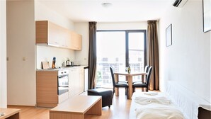 A compact hotel room with a kitchenette, a dining area, and a bed. - Sunny Beach Retreat - 2-bedroom Apartment (Sunny Beach)