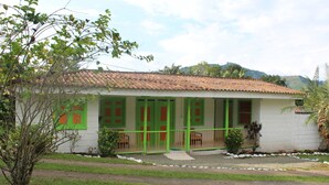 A single-story house with a tiled roof, green-framed windows, and a small porch. - Finca Hotel la Floresta Verde (Pereira)