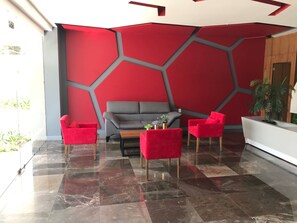 A modern lobby with a geometric red wall, a grey sofa, and red armchairs. - Minerva Zone Apartment Super Vista Fully Equipped Pool 3 Rec 6pp tv Wifi Aa (Guadalajara)