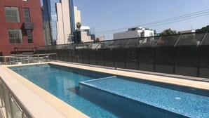 A rectangular swimming pool with clear blue water, surrounded by a beige deck and a black mesh fence. - Minerva Zone Apartment Super Vista Fully Equipped Pool 3 Rec 6pp tv Wifi Aa (Guadalajara)