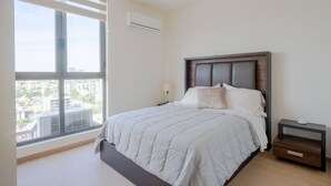 A bedroom with a large window, a bed, a bedside table, and an air conditioning unit. - Minerva Zone Apartment Super Vista Fully Equipped Pool 3 Rec 6pp tv Wifi Aa (Guadalajara)