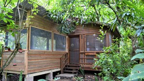A wooden cabin with a large window, a door, and a small porch area. - Private 2-bedroom Jungle Cabin in Tropical Garden, San Ignacio (San Ignacio)