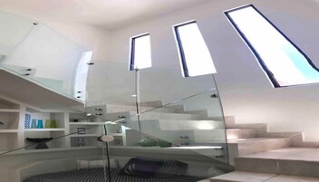 Una escalera moderna con barandillas de vidrio e iluminación integrada.