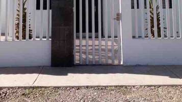 A modern building with a white exterior, a central black section, and a gated entrance.