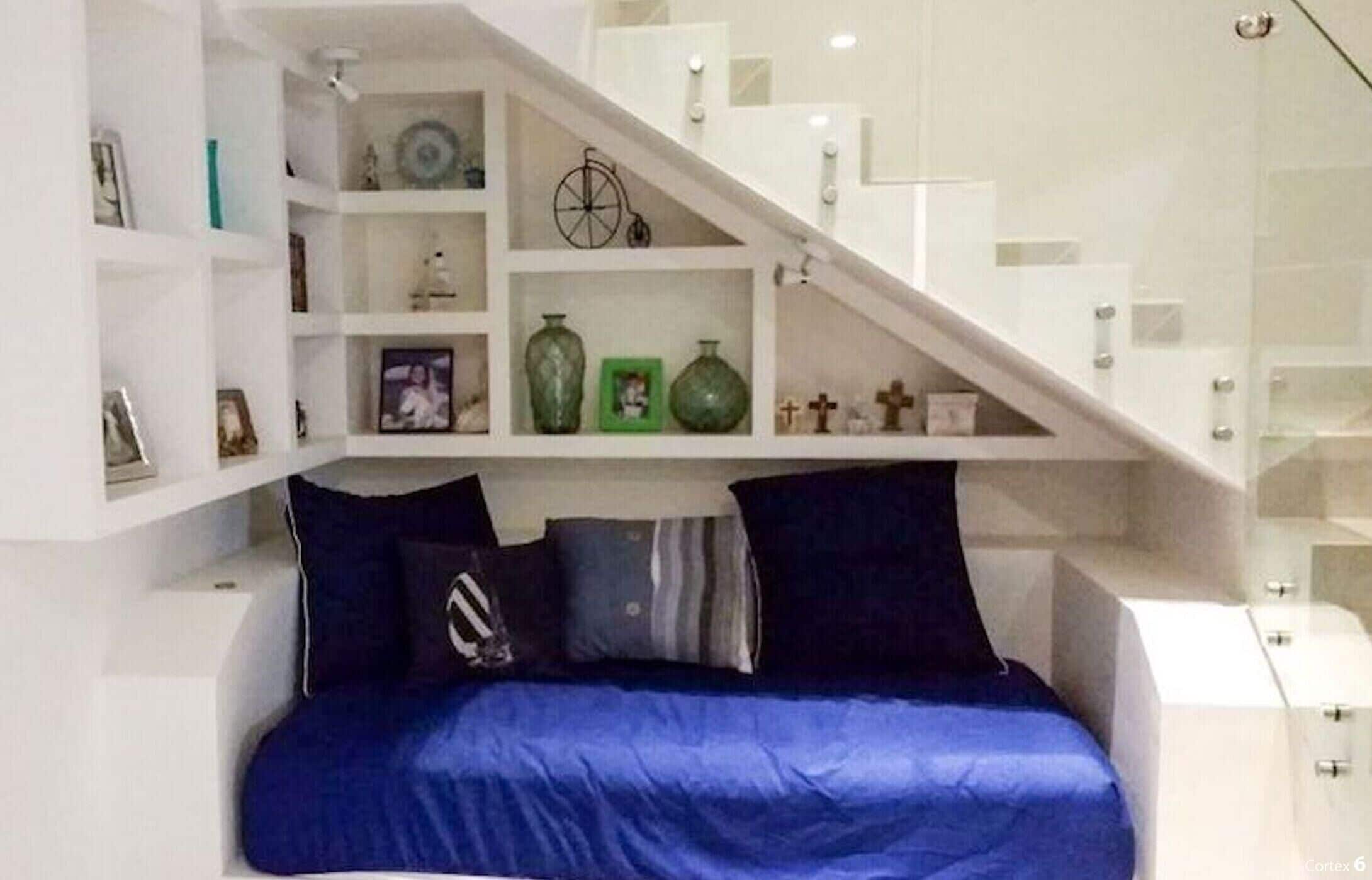 Ein Schlafzimmer mit einem Bett, einer Treppe und eingebauten Regalen mit verschiedenen Gegenständen.