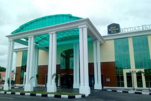 A hotel with a large glass facade, a covered entrance with columns, and a sign reading "Best Western Plus".