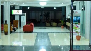 A hotel lobby with a reception desk, seating area, and a television screen. - Best Western Plus Mydas Hotel (Owo)