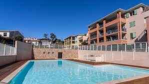 A swimming pool with a wooden deck, surrounded by a stone wall and a white fence. - Le Jardin du Loderi by Interhome (Bormes-les-Mimosas)
