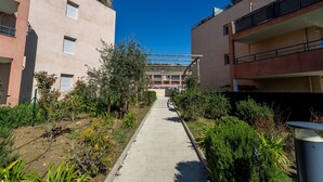 A pathway leading to a building with balconies and a clear blue sky. - Le Jardin du Loderi by Interhome (Bormes-les-Mimosas)