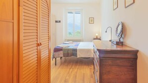 Quarto com cama, cômoda, janela com vista e porta com design veneziano.