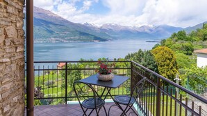 Uma varanda com mesa e cadeiras, vista para um lago e montanhas.