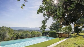 A swimming pool with a wooden deck and a view of distant hills. - Cosy apartment in villa for 3 guests with pool, WIFI, TV and patio (Castelfranco Di Sopra)
