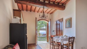 A cozy room with a sofa, a dining table with chairs, a refrigerator, and a wooden ceiling. - Cosy apartment in villa for 3 guests with pool, WIFI, TV and patio (Castelfranco Di Sopra)