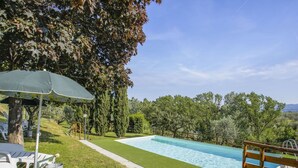 A swimming pool with a wooden deck and a grassy area.