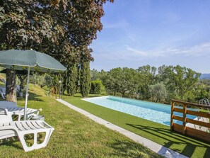 Une piscine avec une terrasse en bois et une zone herbeuse.