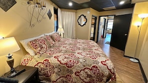Une chambre à coucher avec un grand lit, une table de chevet, une lampe et un luminaire fixé au mur.