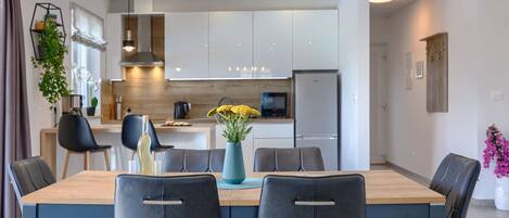 A modern dining area with a rectangular table, four chairs, and a hanging light fixture.