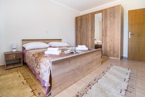 A bedroom with a wooden bed, a nightstand, a wardrobe, and a patterned rug.