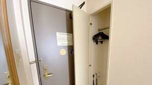A narrow hallway with a door on the left and a closet with hanging items on the right. - Smile Hotel Kitaasaka (Asaka)