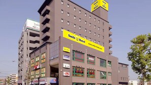 A multi-story building with a prominent yellow sign for Smile Hotel. - Smile Hotel Kitaasaka (Asaka)