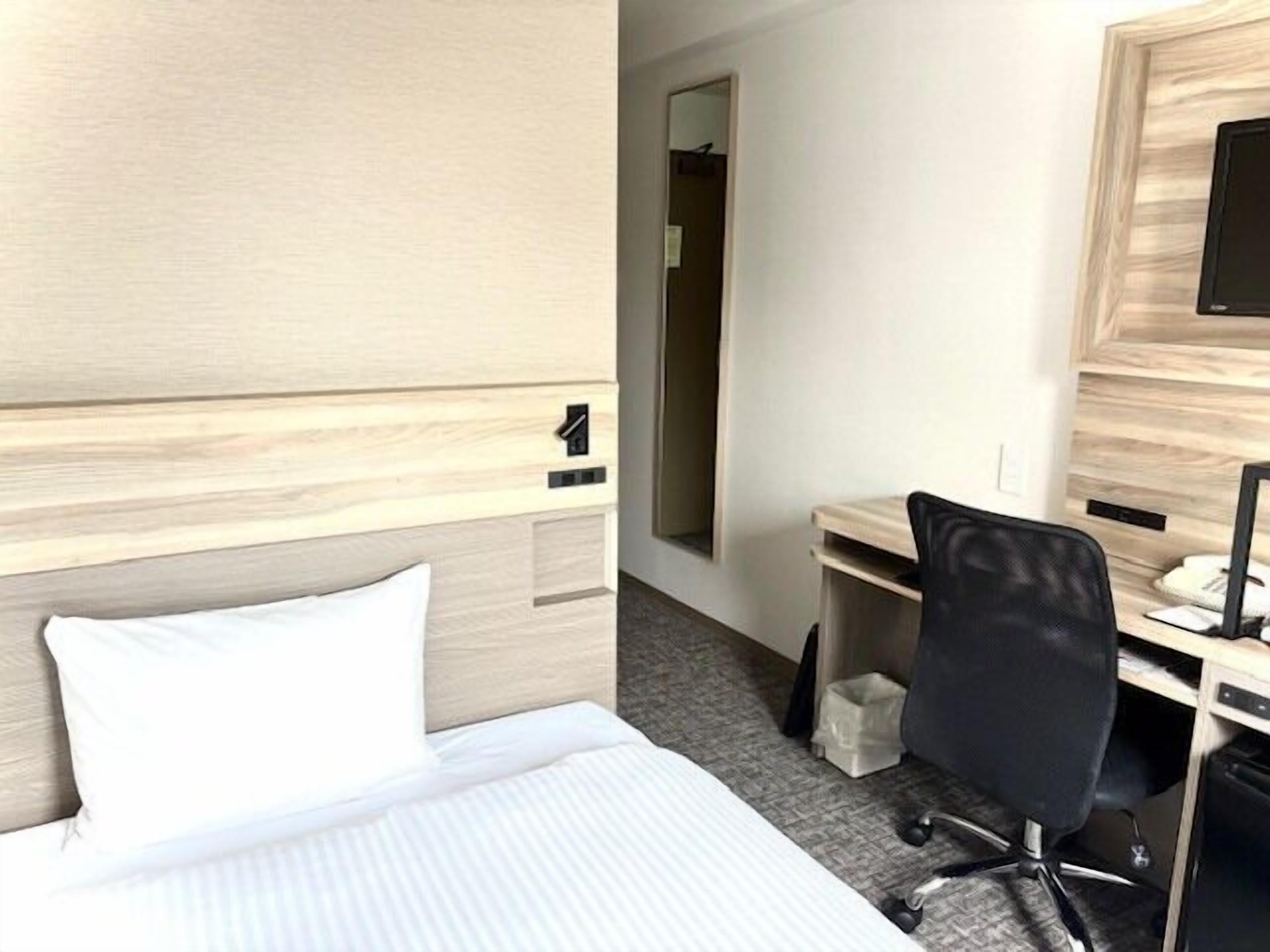 Een hotelkamer met een bed, een bureau, een stoel en een spiegel.