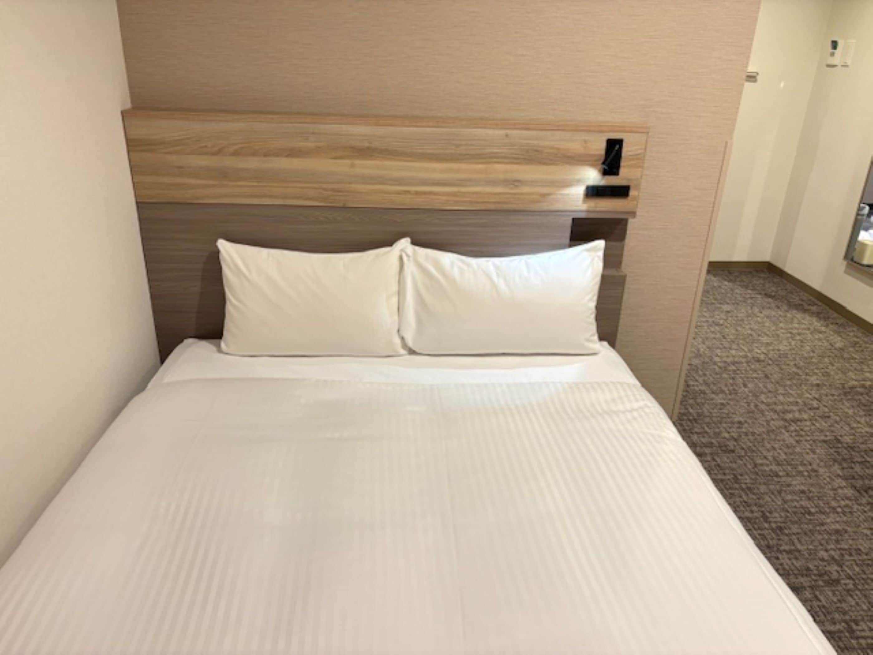A hotel room with a bed, a headboard, and a carpeted floor.