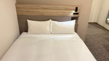 A hotel room with a bed, a headboard, and a carpeted floor.