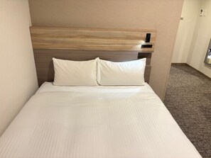 Habitación de hotel con cama, cabecera y piso alfombrado.