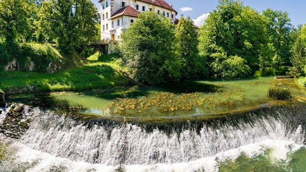 A historic building with a large garden and a waterfall.