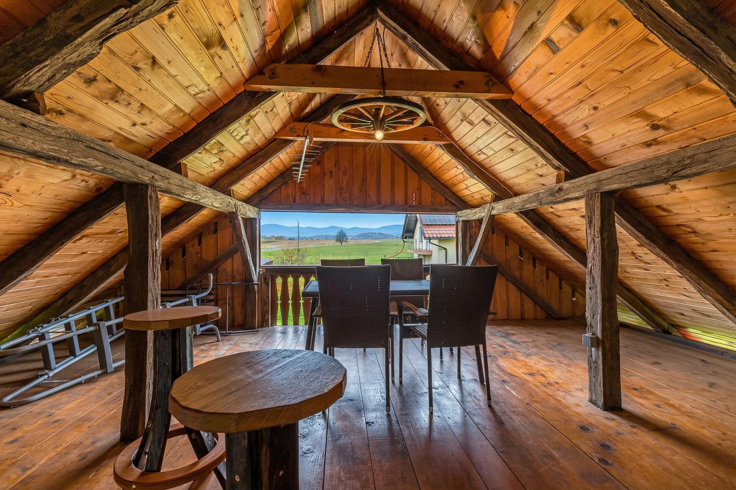 Un intérieur en bois avec une table et des chaises, une vue sur l’extérieur et un ventilateur de plafond.