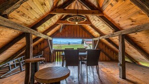 A wooden interior with a table and chairs, a view of the outdoors, and a ceiling fan.