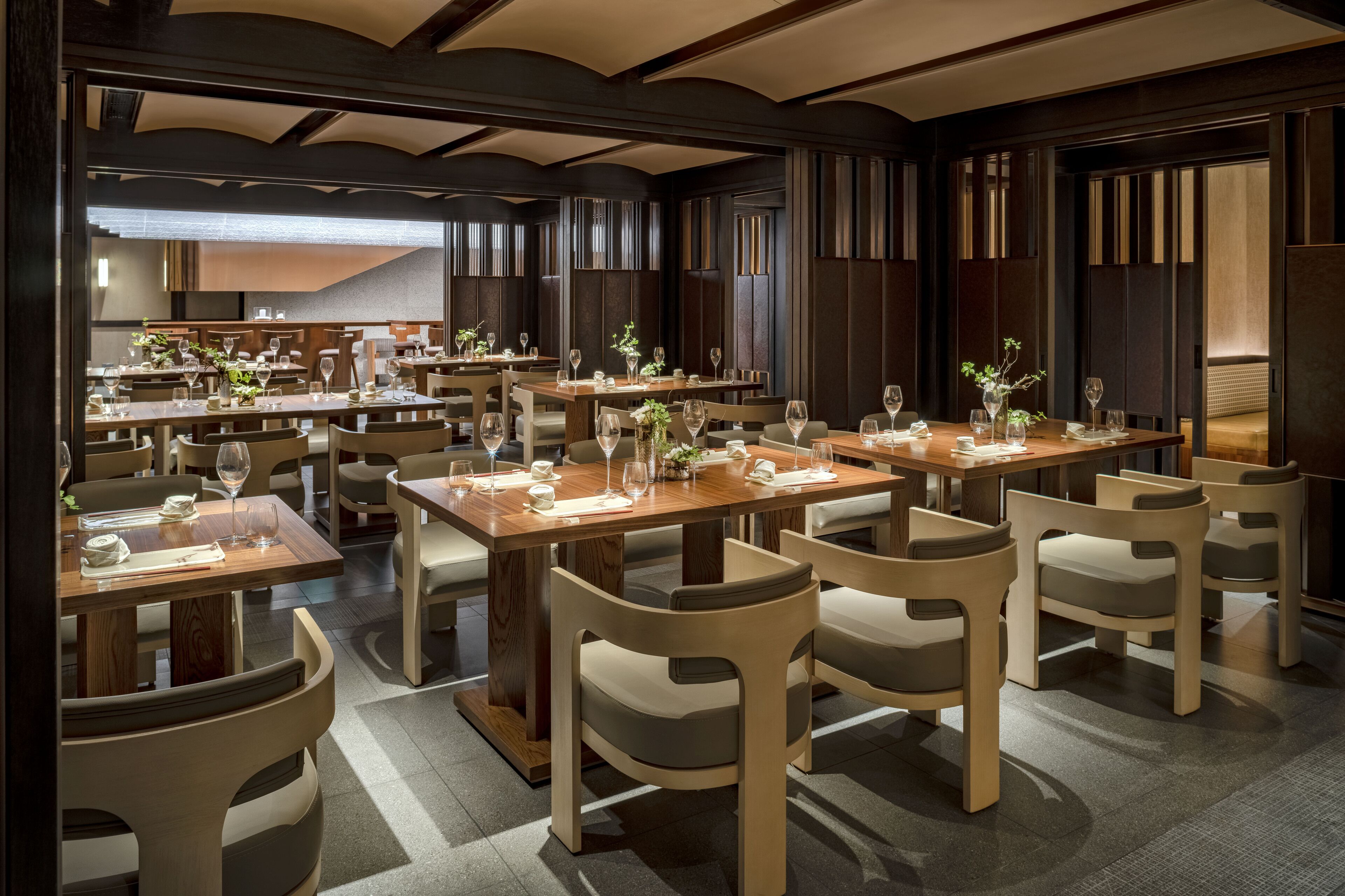 A modern restaurant with wooden tables and chairs, arranged in a spacious layout.