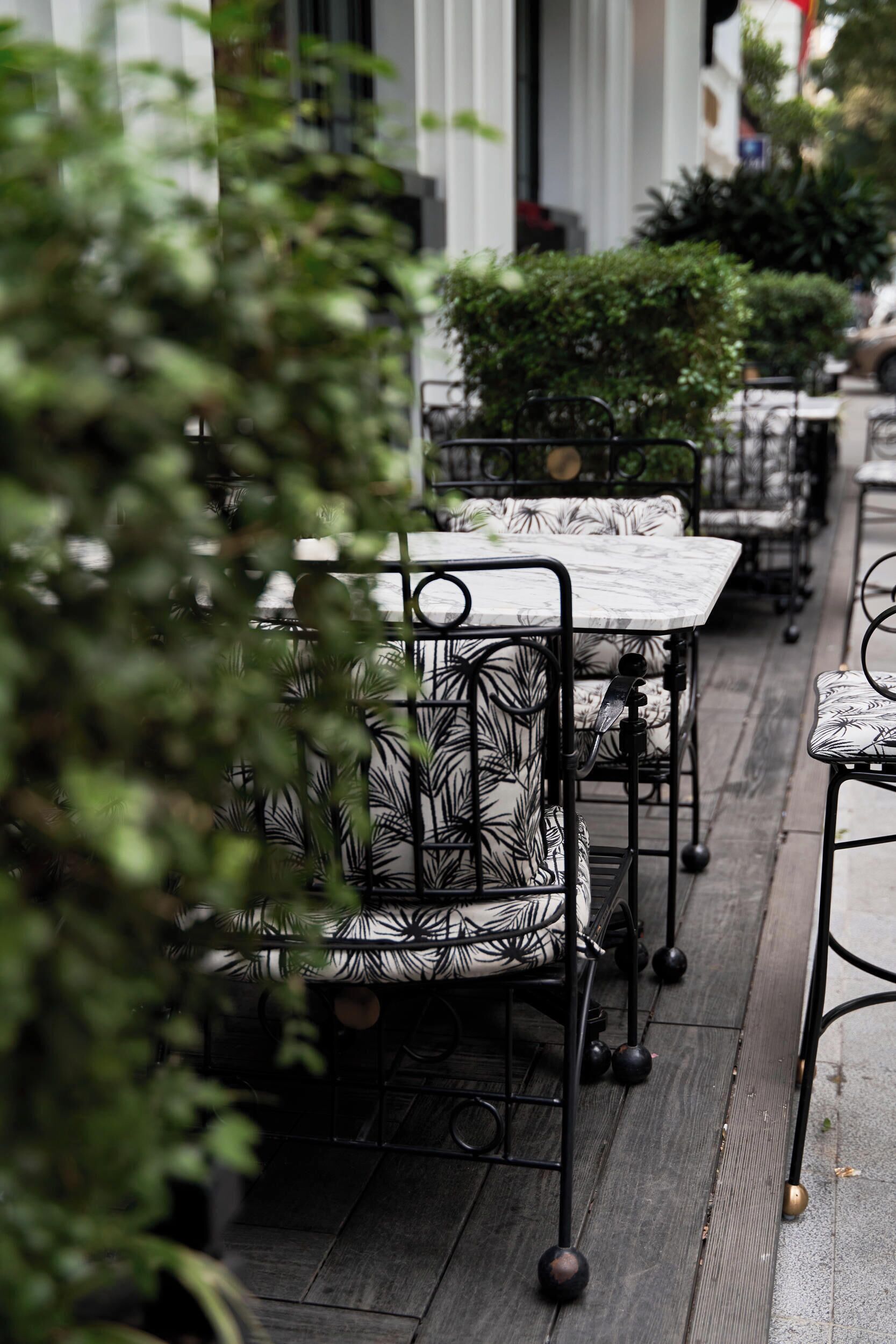 Outdoor seating with patterned cushions, metal tables, and a wooden floor.