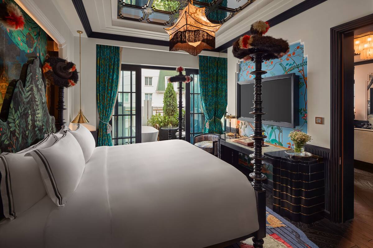 A spacious bedroom with a large bed, a desk, and a view of the city.