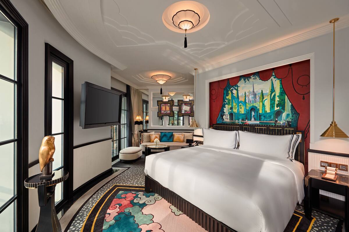 A hotel room with a large bed, a flat-screen TV, a painting on the wall, and a decorative owl statue.
