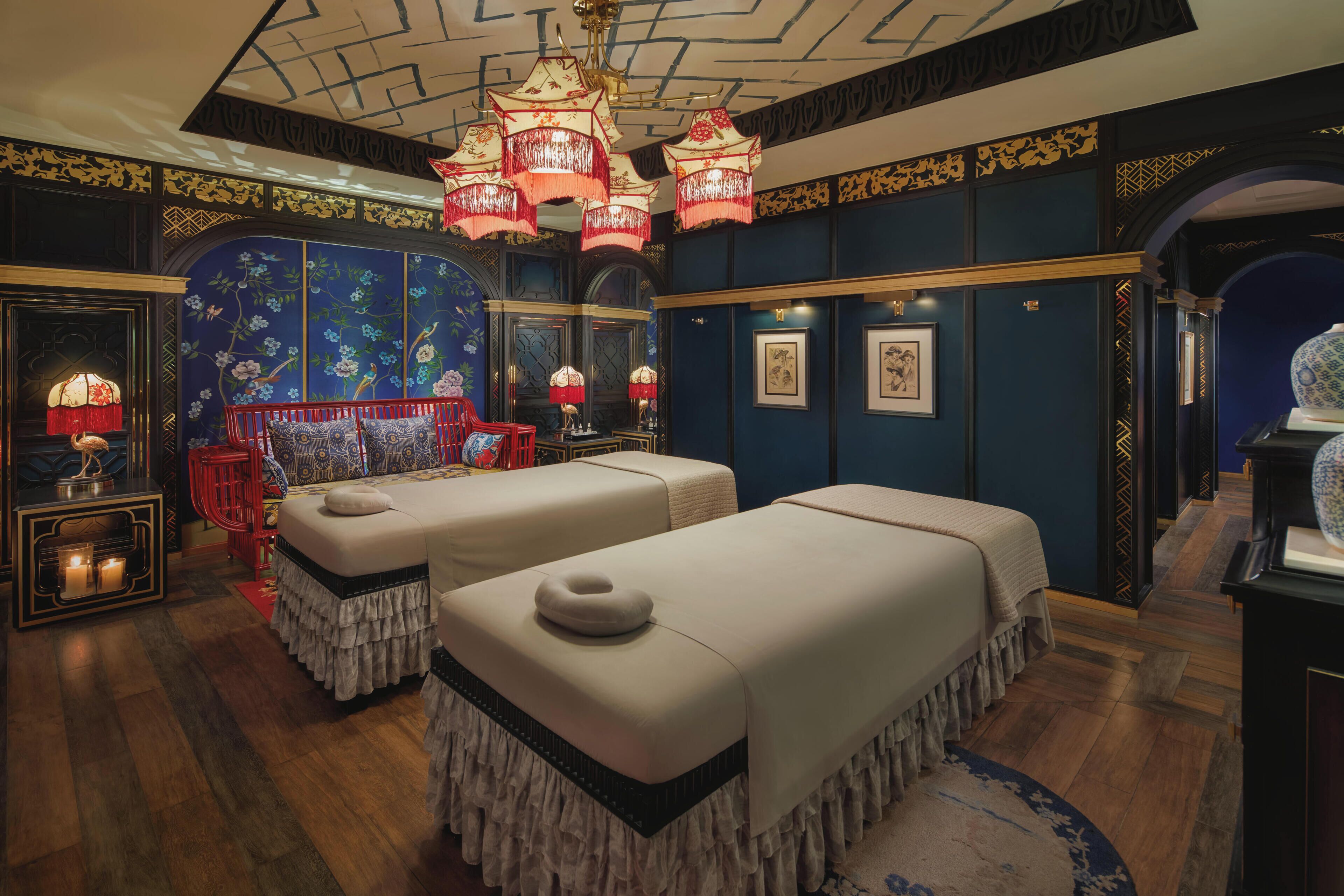 A room with two beds, ornate wall decorations, and a chandelier.