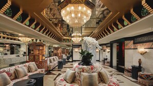 A luxurious lobby with a central floral sofa, multiple seating areas, and a grand chandelier. - Capella Hanoi (Hanoi)