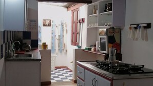 A narrow kitchen with a checkered floor, a stove, and cabinets. - Casa Dalima, home between mountains (Villa de leyva)